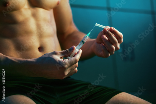 Close up of muscular athlete with injection of steroids. photo