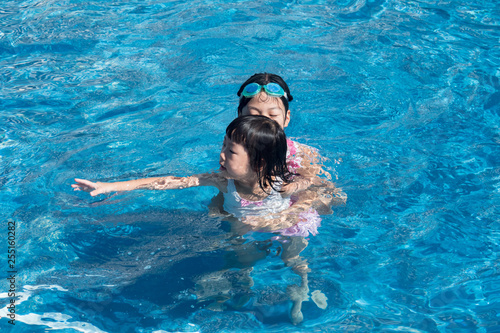 真夏のプールで遊んでいる子供姉妹