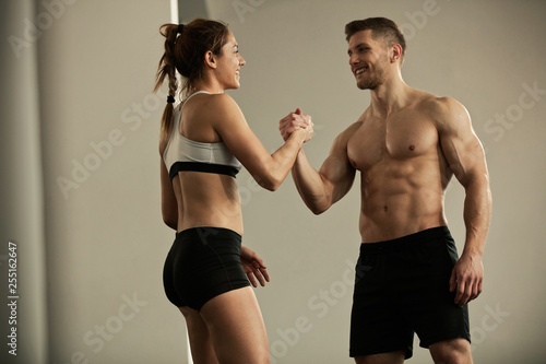 Happy athletic couple greeting each other in a gym.