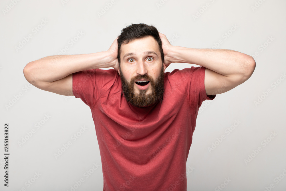 Image of emotional man 30s with beard and mustache grabbing head while standing Image of emotional man 30s with beard and mustache grabbing head while standing