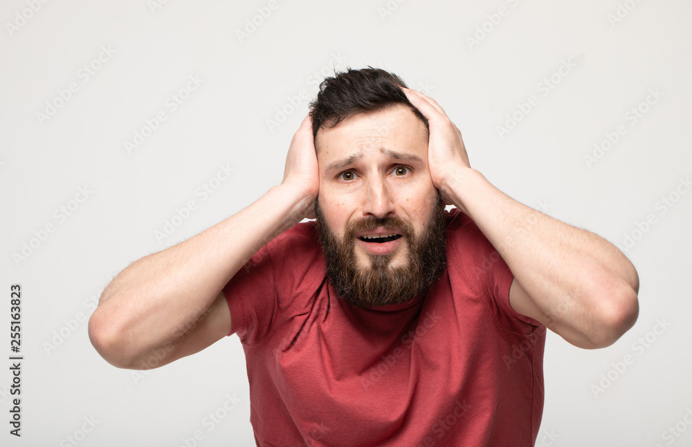 Image of emotional man 30s with beard and mustache grabbing head while standing Image of emotional man 30s with beard and mustache grabbing head while standing