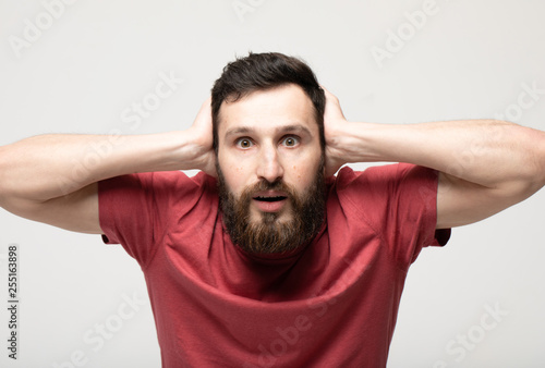 Image of emotional man 30s with beard and mustache grabbing head while standing