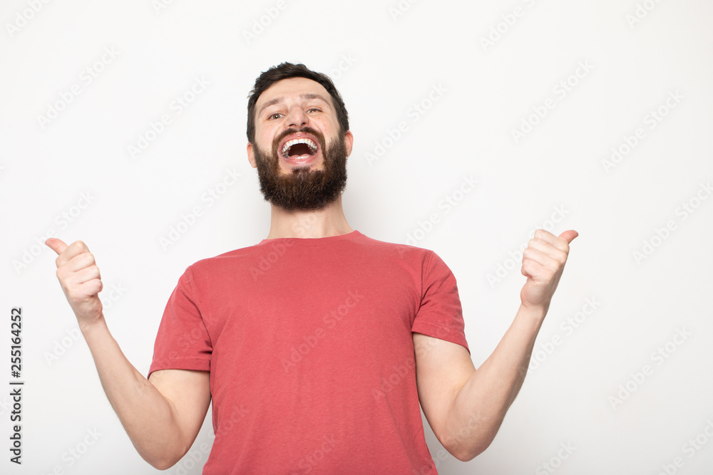 Portrait of a cheerful young man wearing casual clothes standing isolated over grey background, using mobile phone. Portrait of a cheerful young man wearing casual clothes standing isolated over grey background, using mobile phone.