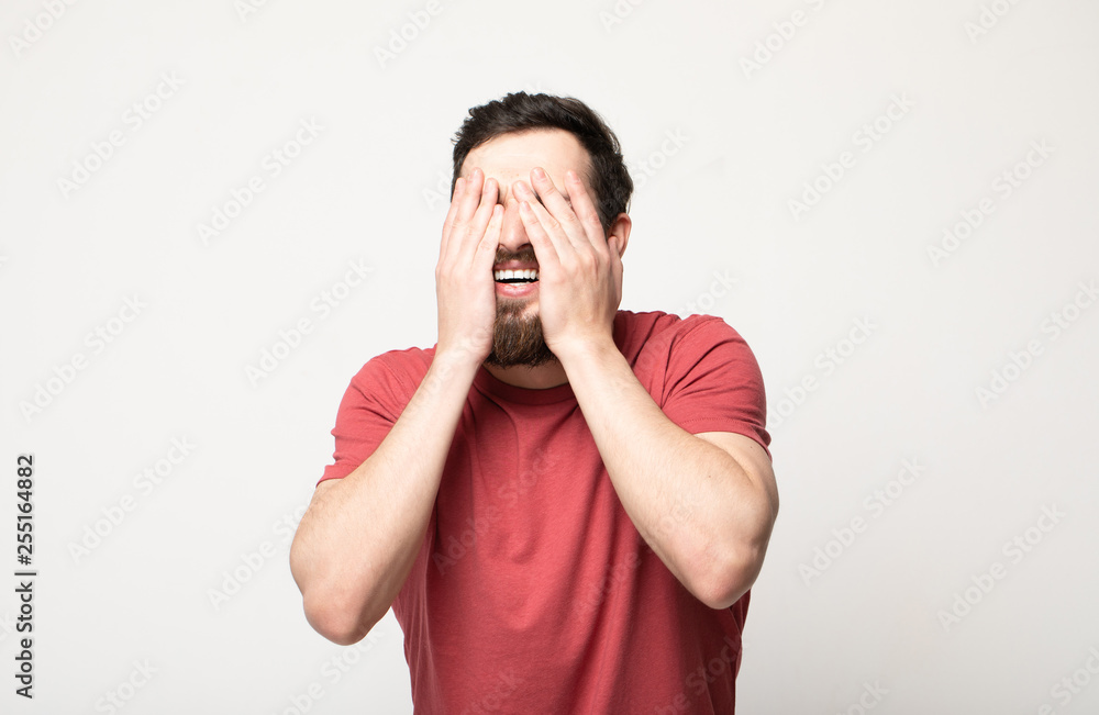smiling man closing his eyes over gray background smiling man closing his eyes over gray background