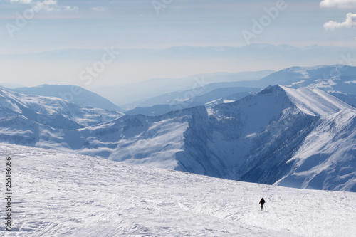 Silhouette of skier on snowy off-piste slope and mountains in haze © BSANI
