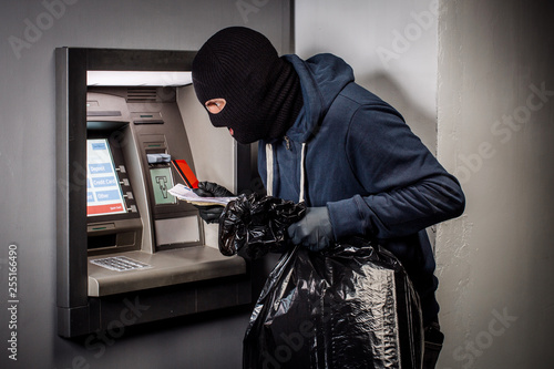 Thief. Hacker stealing money from ATM machine. Phishing, ATM skimming
