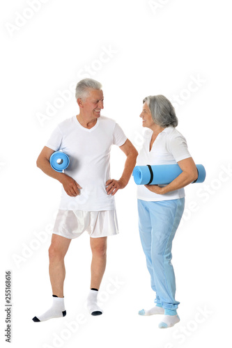 Portrait of senior couple with fitness mats on white background