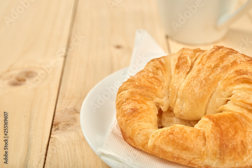 Coffee cup and fresh baked croissants on wooden table