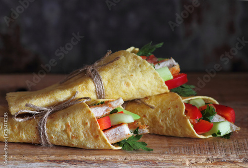 Fresh tortilla wraps with vegetable filling and grilled chicken on wooden table