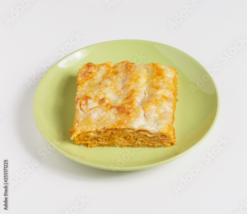 A piece of lasagna on a plate on a white background.