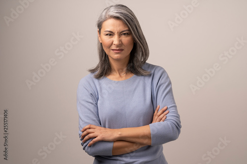 Aggressive Mongolian Woman with Gray Hair on a Gray Background.