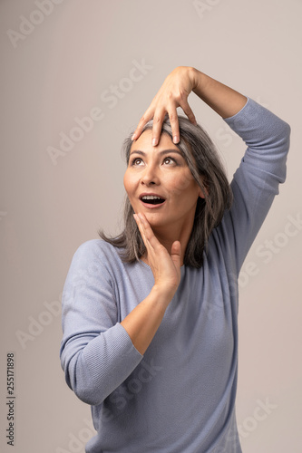 Attractive Asian woman is emotionally posing touching her head with hands