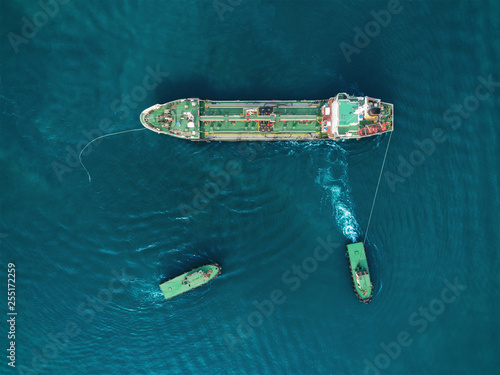 Aerial top view Tugboat drag Oil ship tanker to ship bridge for load oil from refinery for transportation.