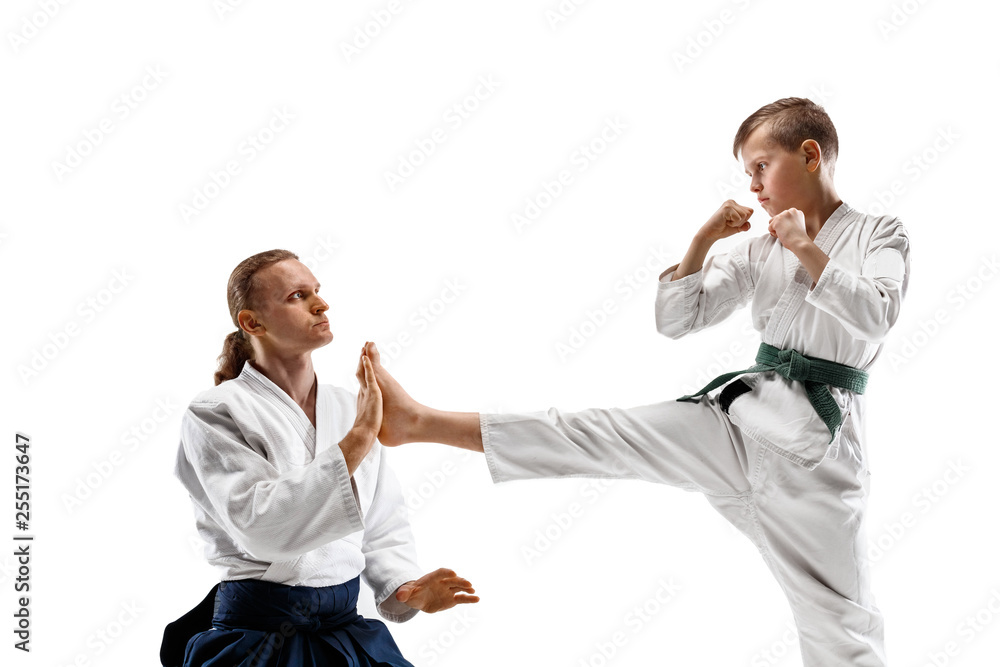 Man and teen boy fighting at Aikido training in martial arts school. Healthy lifestyle and sports concept. Fightrers in white kimono on white background. Karate men with concentrated faces in uniform. Man and teen boy fighting at Aikido training in martial arts school. Healthy lifestyle and sports concept. Fightrers in white kimono on white background. Karate men with concentrated faces in uniform.
