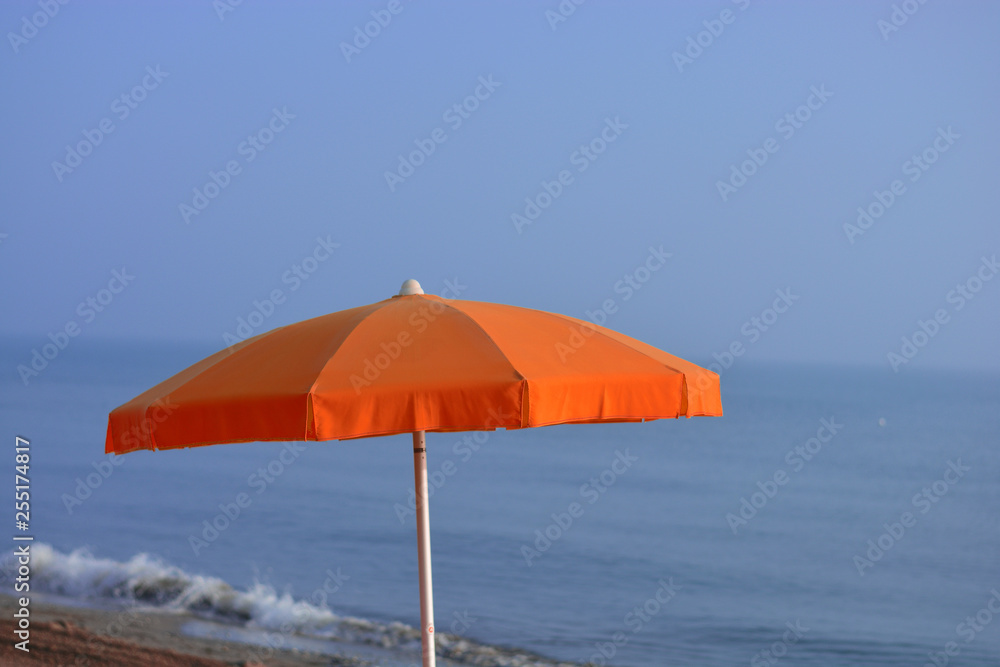 a red beach umbrella, with the sea in the background