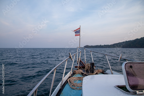 the bow of a boat sailing into the sea with the Thai flag