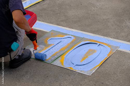 A painter painting parking lots blue lines striping in a car park.