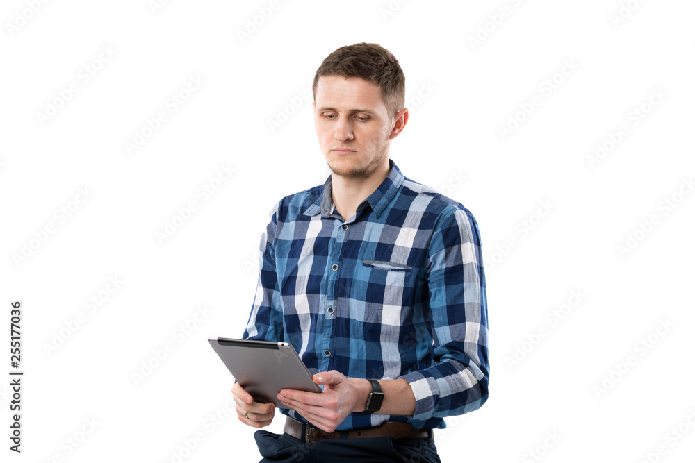 A young Caucasian man with a tablet in his hands is sitting on a white isolate background. Theme portrait of a man, an employee is a sales manager salesman with a technology computer in his hands A young Caucasian man with a tablet in his hands is sitting on a white isolate background. Theme portrait of a man, an employee is a sales manager salesman with a technology computer in his hands