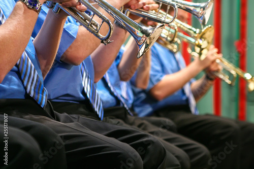 background of the concert hall and a number of male musicians play wind instruments trumpets. musicians in black trousers and blue shirts