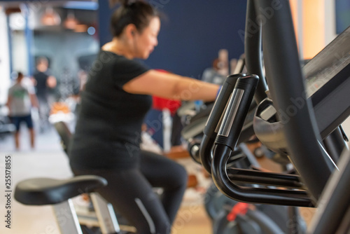 Blurred view of woman exercising on cycling machine in gym