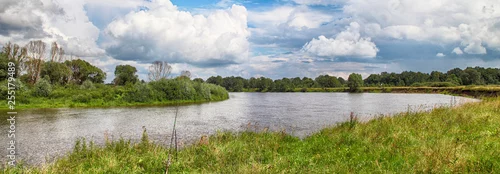 Panel kuchenny z motywem Panorama of the summer landscape with a view of the river and field. Fishing on a pond on a warm day, fishing rods and feeders are thrown into the water.