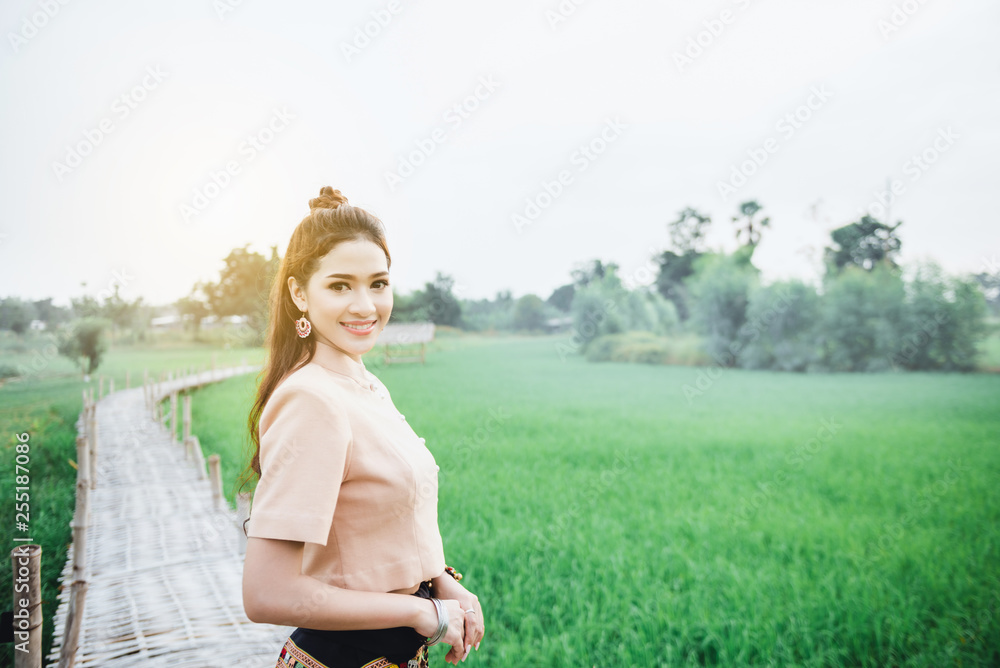 Beautiful Asian woman in local dress standing and enjoy natural on bamboo bridge in rice field Beautiful Asian woman in local dress standing and enjoy natural on bamboo bridge in rice field