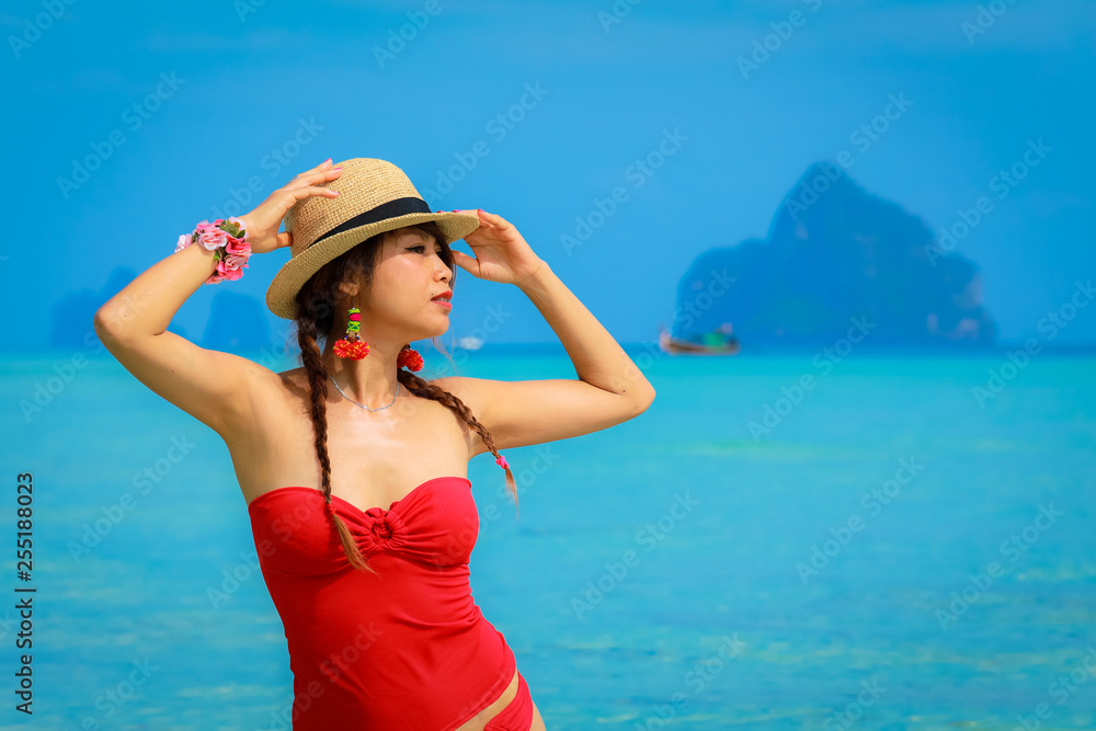 Young asain woman in red bikini under sunlight with turquoise color deep sea as background. Tropical island paradise holiday travel