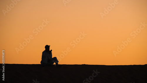 Man on sand dune talking on mobile phone