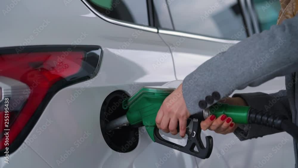 Woman fills petrol into her car at a gas station closeup
