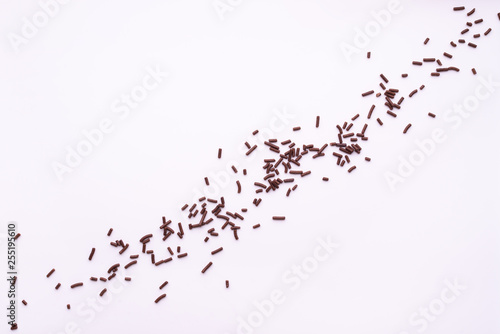 chocolate sprinkles over white background  flat lay