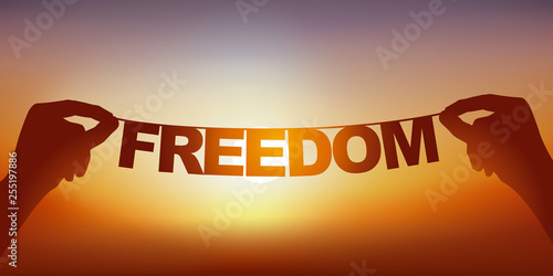 Concept de l’esprit libre, avec deux mains qui tiennent une guirlande sur laquelle est écrit le mot liberté devant un ciel ensoleillé.