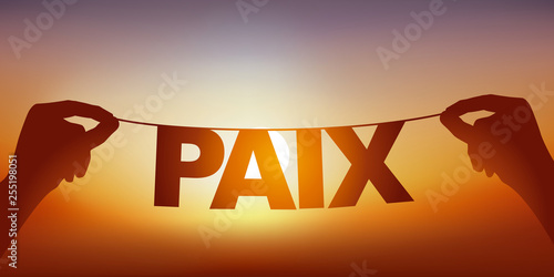 Concept de la paix et la tranquillité, avec deux mains qui tiennent une guirlande sur laquelle est écrit le mot paix, devant un ciel ensoleillé.