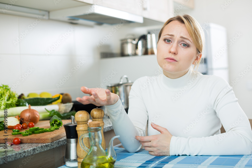 Miserable young woman in domestic kitchen