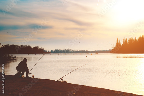 Fisherman with a fishing rod on the river bank. Evening