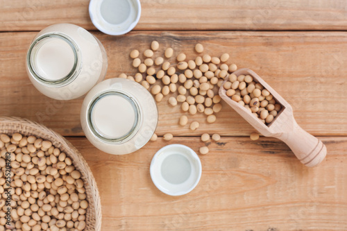 Bottle of soy milk and soy beans on wood background.