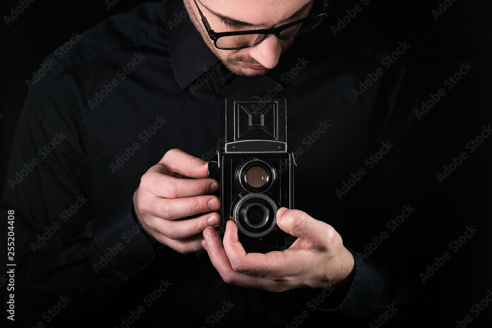 Man photographer holding a camera. Shooting process. Retro photo camera medium format twin-lens reflex camera on a black background. Man photographer holding a camera. Shooting process. Retro photo camera medium format twin-lens reflex camera on a black background.
