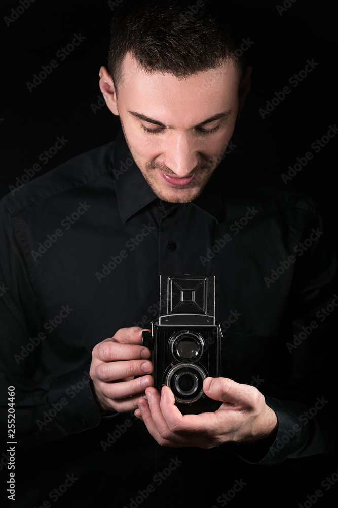 Man photographer holding a camera. Shooting process. Retro photo camera medium format twin-lens reflex camera on a black background. Man photographer holding a camera. Shooting process. Retro photo camera medium format twin-lens reflex camera on a black background.