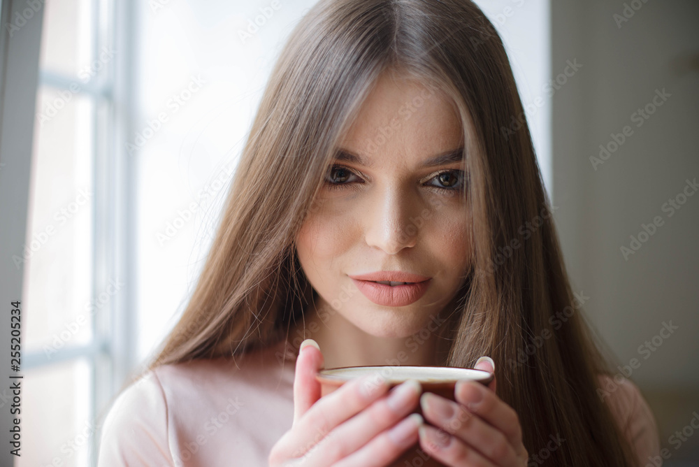 Beautiful girl is drinking coffee and smiling while sitting at the cafe Beautiful girl is drinking coffee and smiling while sitting at the cafe