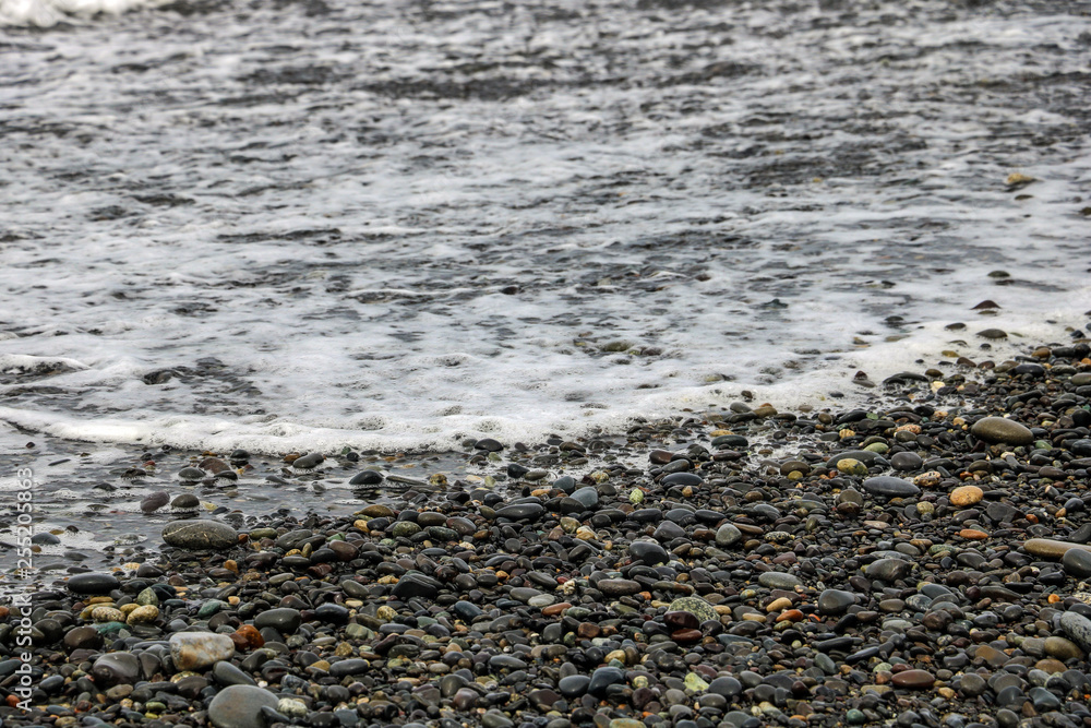Pebbles on a sandy beach, shiny wet stones and waves. Pebbles on a sandy beach, shiny wet stones and waves.