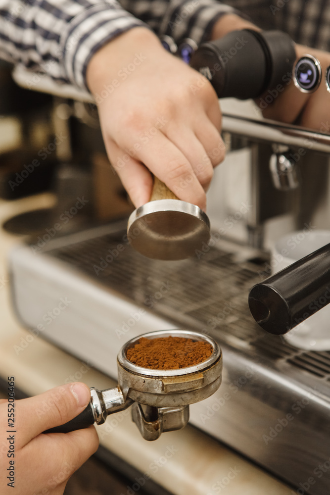 Vertical cropped shot of a barista preparing coffee using tamper for presing ground coffee into portafilter professionalism cafe working morning breakfast small business occupation job brewing concept