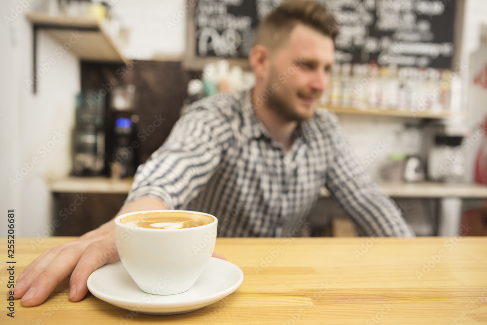 Selective focus on a cup of fresh coffee barista working at his coffee shop on the background copyspace profession occupation job entrepreneur owner startup small business businessman casual hipster Selective focus on a cup of fresh coffee barista working at his coffee shop on the background copyspace profession occupation job entrepreneur owner startup small business businessman casual hipster