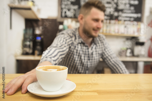 Selective focus on a cup of fresh coffee barista working at his coffee shop on the background copyspace profession occupation job entrepreneur owner startup small business businessman casual hipster © mad_production