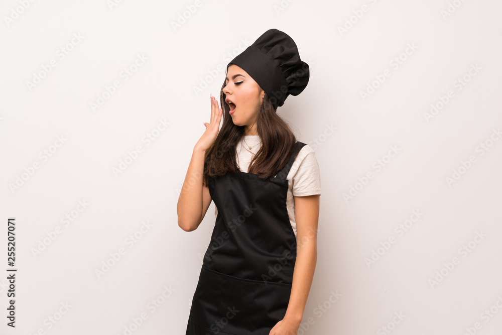 Teenager chef over white wall yawning and covering wide open mouth with hand Teenager chef over white wall yawning and covering wide open mouth with hand