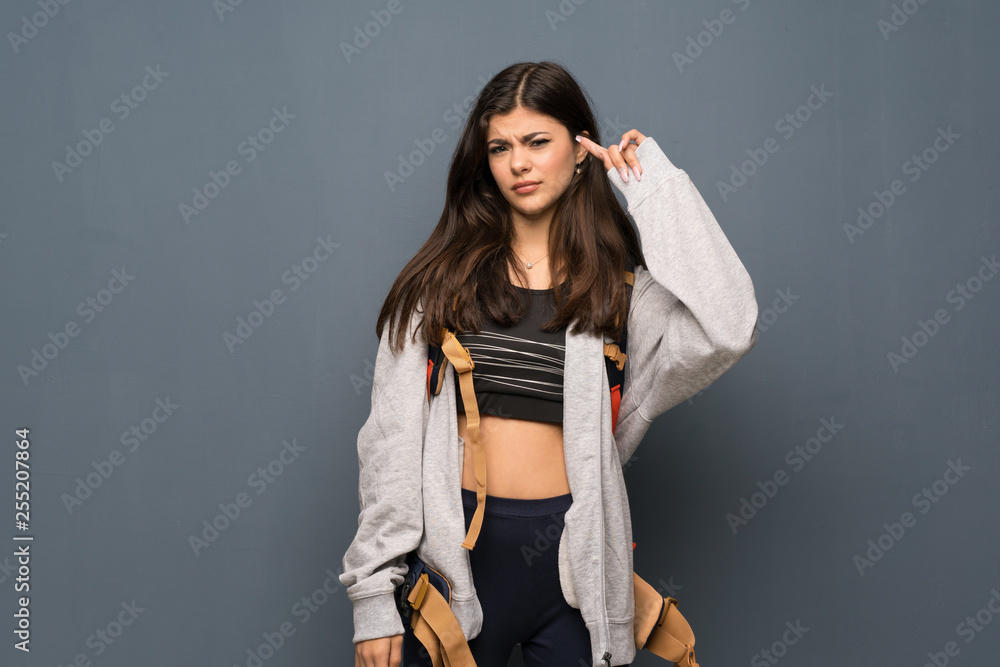 Teenager traveler girl over wall making the gesture of madness putting finger on the head Teenager traveler girl over wall making the gesture of madness putting finger on the head