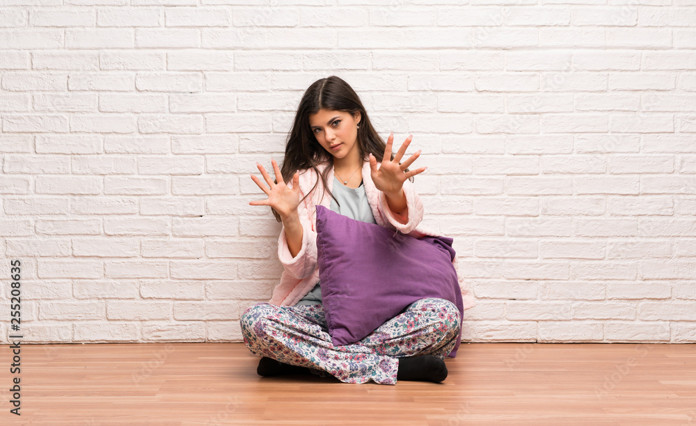 Teenager girl in pajamas nervous and scared stretching hands to the front Teenager girl in pajamas nervous and scared stretching hands to the front