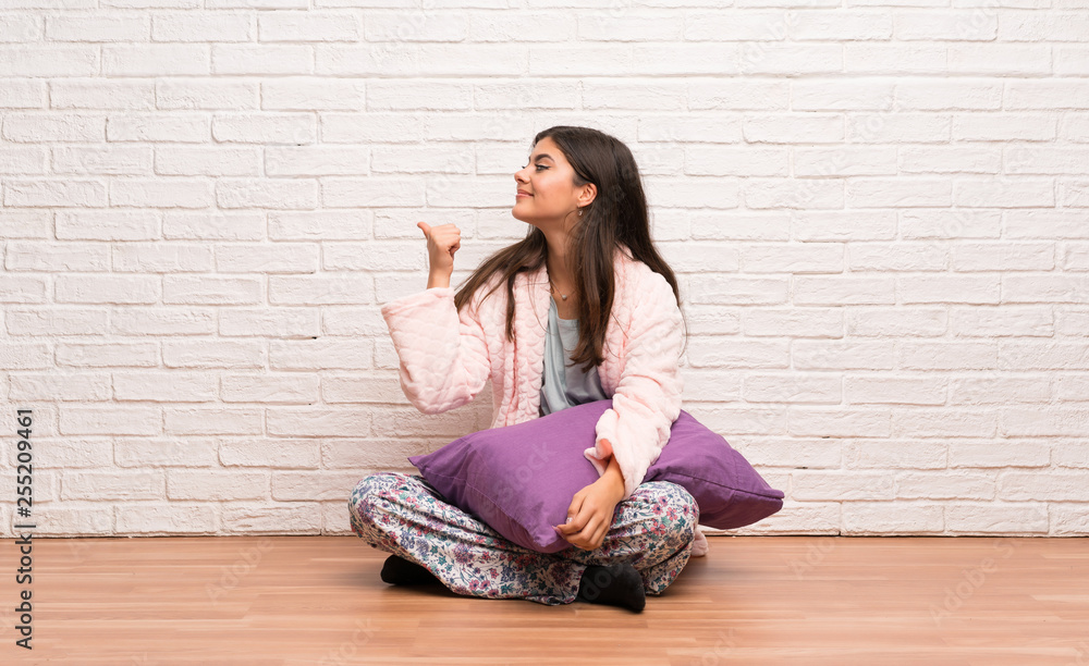 Teenager girl in pajamas pointing back Teenager girl in pajamas pointing back