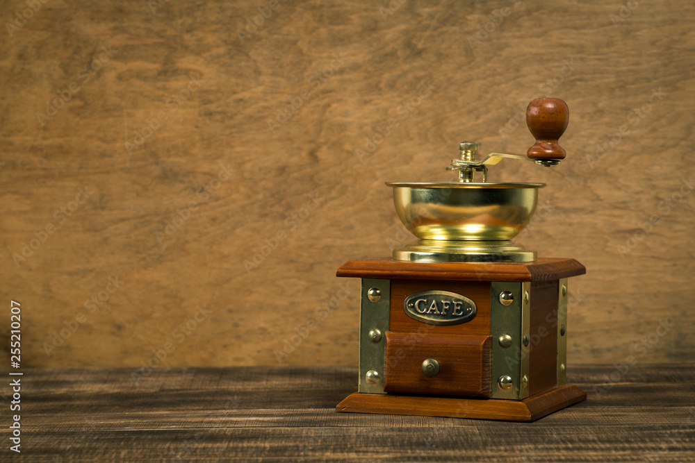 Obraz na plátně Vintage manual coffee grinder on wooden table with color wall background