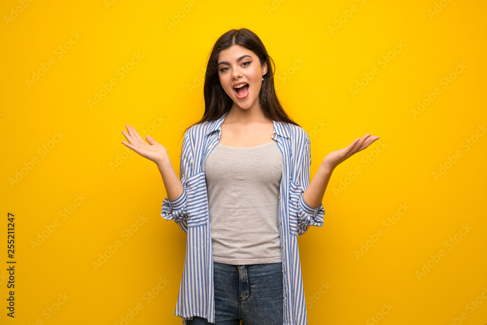 Teenager girl over yellow wall with shocked facial expression Teenager girl over yellow wall with shocked facial expression