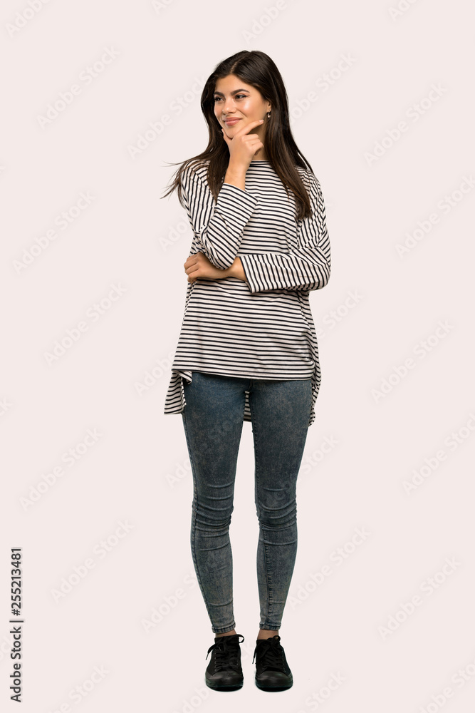 A full-length shot of a Teenager girl with striped shirt looking to the side over isolated background A full-length shot of a Teenager girl with striped shirt looking to the side over isolated background