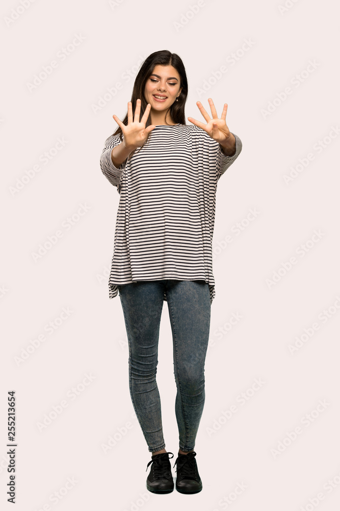 A full-length shot of a Teenager girl with striped shirt counting nine with fingers over isolated background A full-length shot of a Teenager girl with striped shirt counting nine with fingers over isolated background